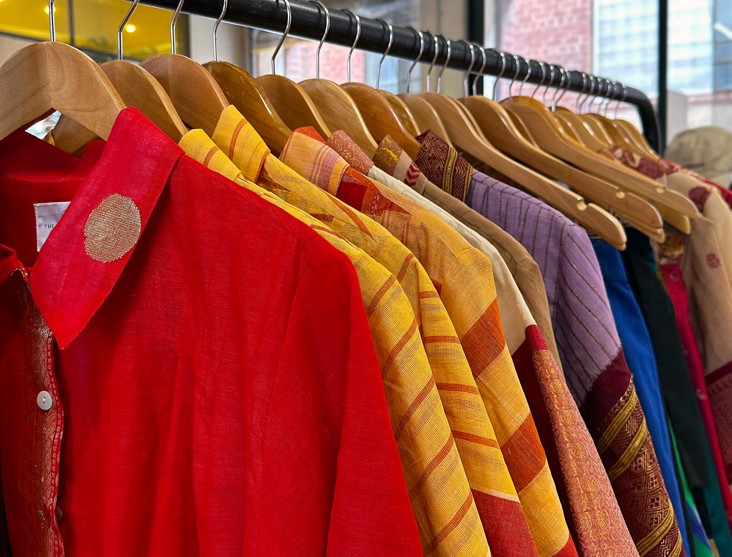 A rack of dresses in front of a window